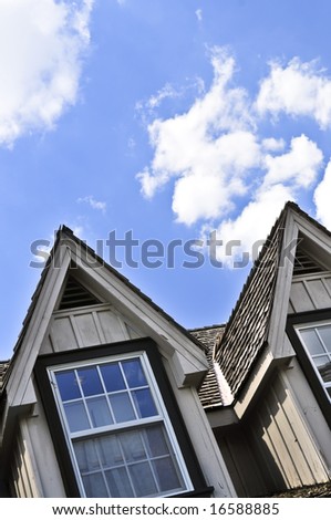 Window dormers on a house with wooden shingles on blue sky background