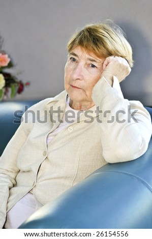 Sad elderly woman sitting on a couch indoors