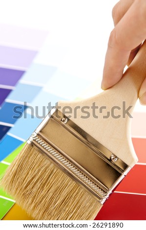 Hand holding paintbrush over color card samples