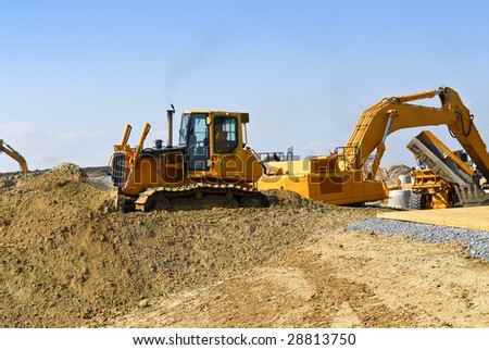 Yellow bulldozer machines digging and moving earth at construction site