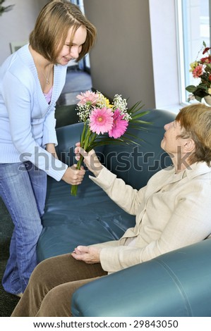 Granddaughter bringing colorful flowers to her grandmother