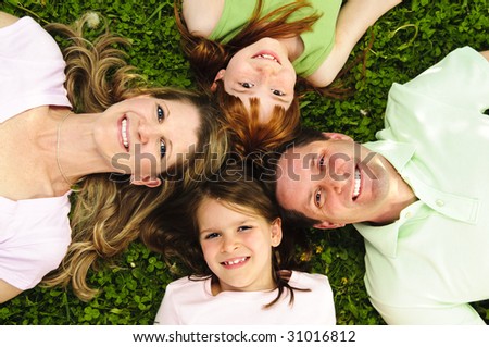 Portrait of happy family laying  on grass looking up heads together
