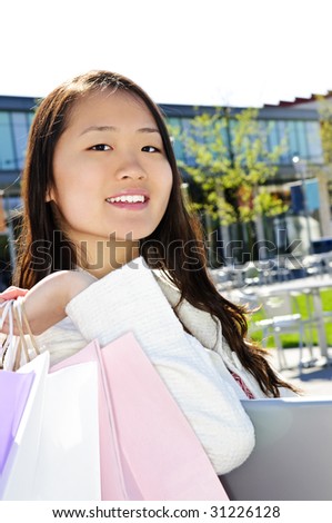Young korean woman with shopping bags at outdoor mall sitting on bench