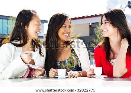 Group of girl friends sitting and having drinks at outdoor cafe