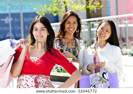 Three young girl friends holding shopping bags at mall