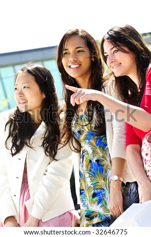 Three young girlfriends at outdoor mall pointing