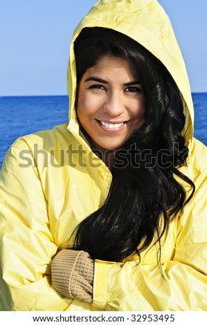 Portrait of beautiful smiling brunette girl wearing yellow raincoat