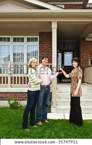 Happy couple getting keys to new house from real estate agent