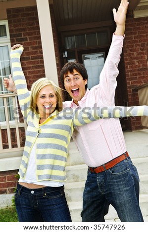 Young excited couple celebrating in front of home