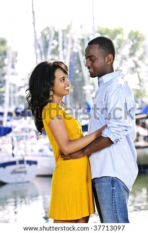 Young romantic couple facing each other hugging and standing at harbor