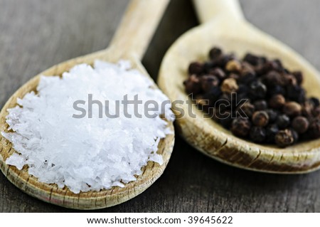 Sea salt and whole peppercorns on wooden spoons