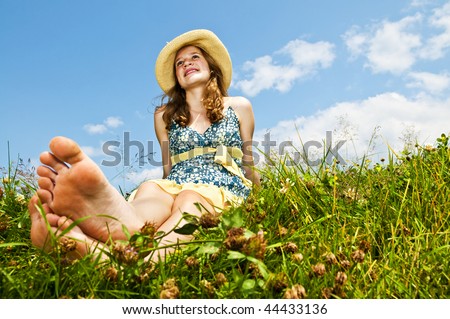 stock photo Young teenage girl sitting on summer meadow barefoot