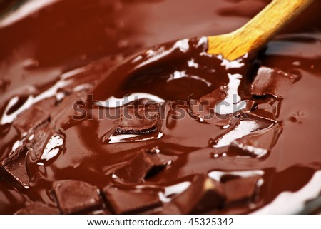 Wooden spoon stirring melting rich chocolate chunks