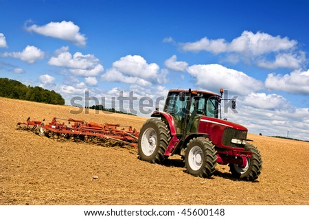 Small scale farming with tractor and plow in field