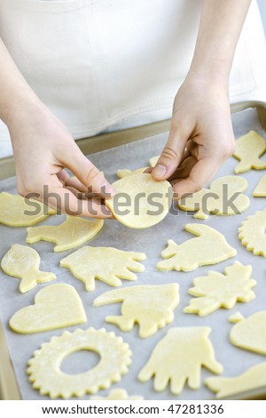 Chef placing cutout cookie dough shapes on tray for baking