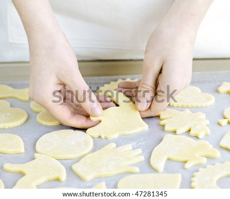 Chef placing cutout cookie dough shapes on tray for baking