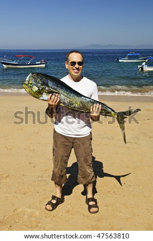 Happy tourist holding his big fish catch after fishing trip in Mexico