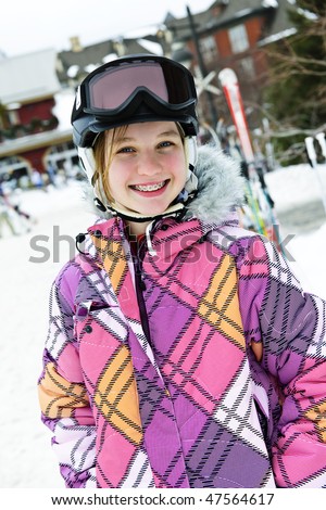 Portrait of happy teenage girl in ski helmet and goggles at winter resort