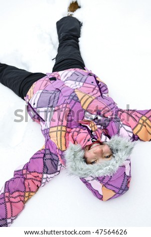 Happy teenage girl making snow angel in winter