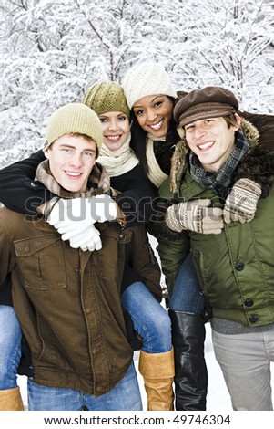 Group of young friends giving piggy back rides outdoors in winter