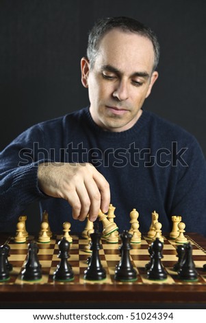 Man moving a chess piece on wooden chessboard