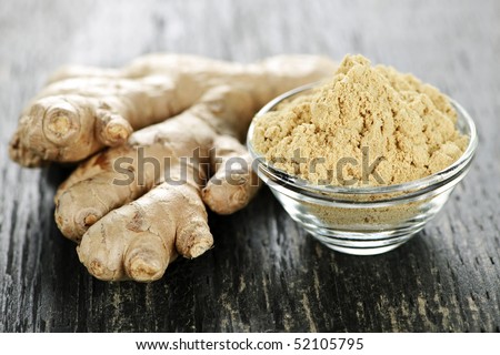 Fresh and ground ginger root spice on wooden table