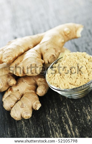 Fresh and ground ginger root spice on wooden table
