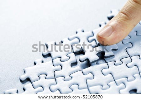 Finger pushing missing puzzle piece into place