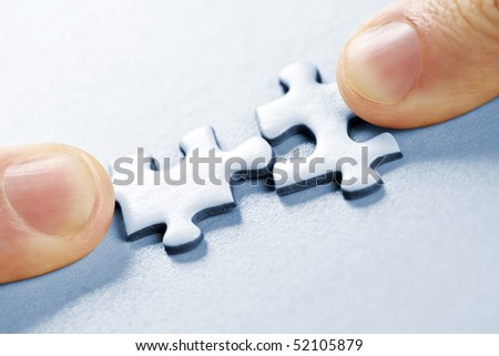 Fingers pushing two matching puzzle pieces together