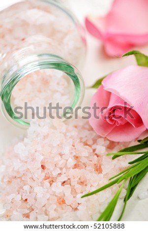Pink bath salts in a glass jar with flowers and herbs