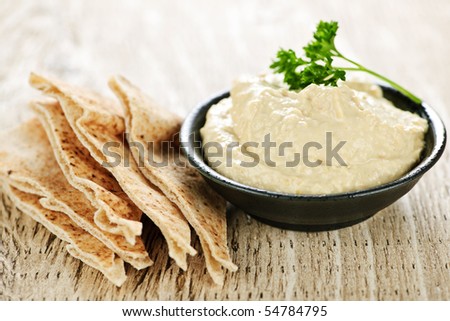 Bowl of fresh hummus dip with pita bread slices