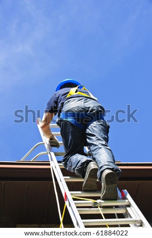 Construction worker climbing extension ladder to roof
