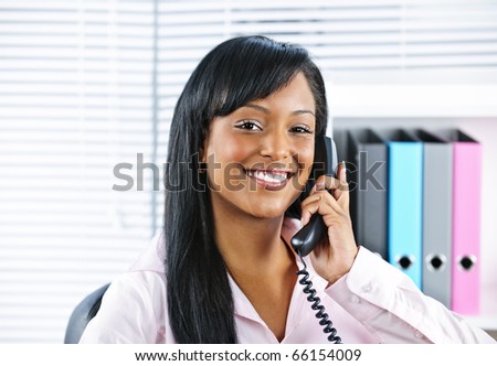 Portrait of smiling black business woman on phone in office