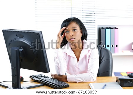Worried young black business woman at desk in office