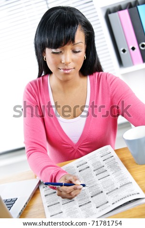 Young black female student looking in newspaper for job