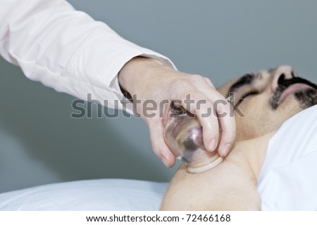 Applying cupping therapy in traditional chinese medicine on man\'s shoulder