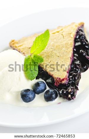 Slice of blueberry pie with vanilla ice cream and berries