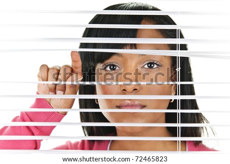 Young black woman looking through horizontal venetian blinds