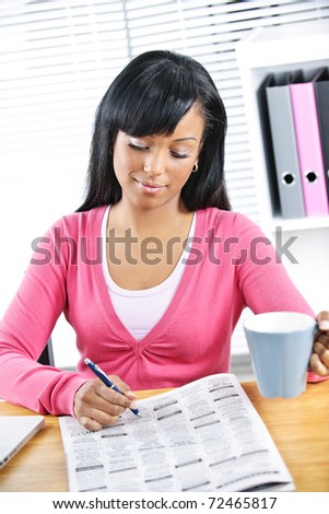 Young black female student looking in newspaper for job