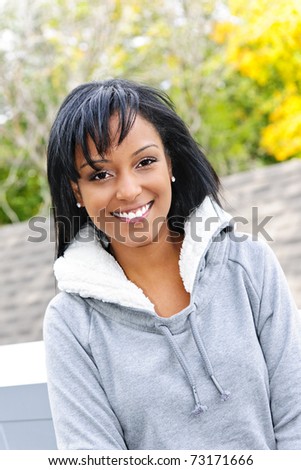 Portrait of happy smiling young black woman outside in the fall