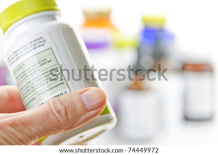 Hand holding medicine bottle to read label