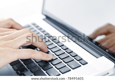 Hands typing on laptop computer keyboard close up
