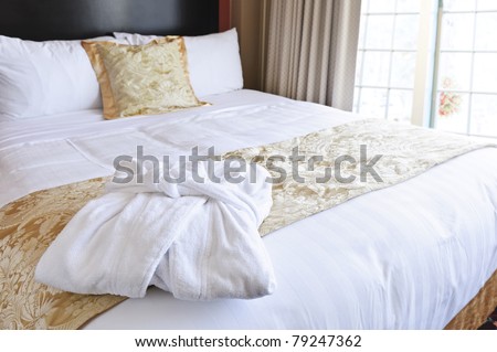 Comfortable bed with clean bathrobe in upscale hotel