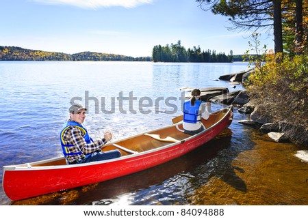 Family in red canoe near rocky shore of Lake of Two Rivers, Ontario, Canada