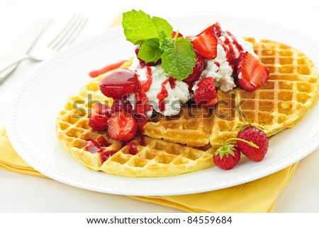 Plate of belgian waffles with fresh strawberries and whipped cream