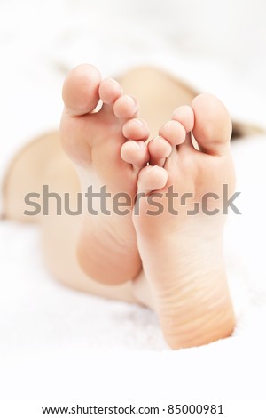 Soles of soft female bare feet crossed in closeup