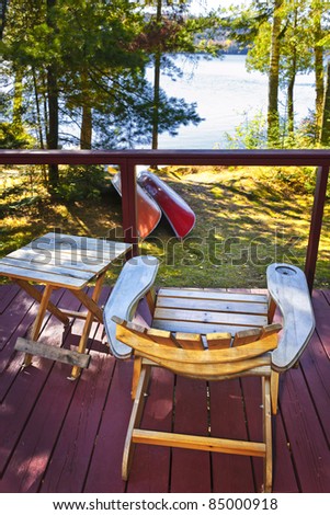 Wooden deck of cottage with lake view and Adirondack chair