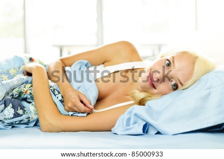 Happy blonde woman laying in bed in the morning at home