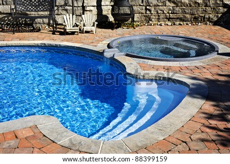 Outdoor inground residential swimming pool in backyard with hot tub