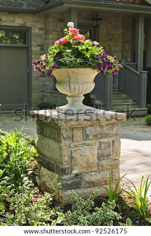 Stone planter with flowers near driveway of house